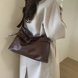 Detail of vintage brown tote bag showing belt buckle design on beige wool coat