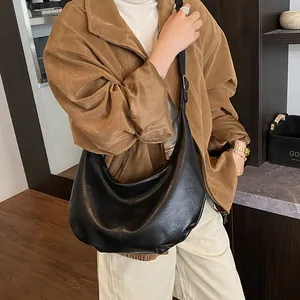 Vue lifestyle d'un grand sac bandoulière demi-lune en cuir noir porté avec style