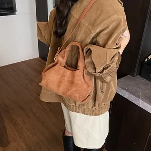 Close-up showing the soft brown suede texture and metal zipper detail of the handbag