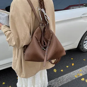 Close-up of brown leather crossbody bag with vertical accordion pleats and metal eyelets