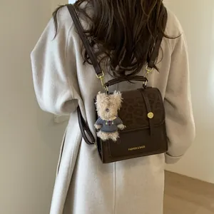 Détail du sac à dos en cuir marron avec rabat léopard et breloque ours en peluche