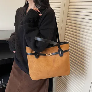 Détail du sac cabas en daim marron avec bandoulière en cuir noir et boucle dorée