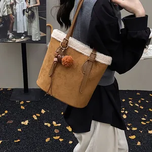 Detail der Wildleder-Eimertasche mit weißem Kunstfellbesatz und dekorativen Anhängern