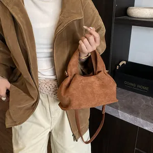 Detail of the brown suede handbag showing rich pleated texture and leather shoulder strap