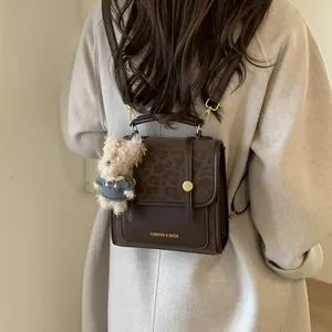 Détail du sac à dos en cuir marron avec rabat léopard et pendentif ours décoratif