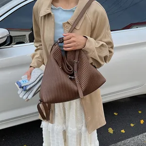 Close-up of a large dark brown pleated shoulder bag with vertical textured stripes