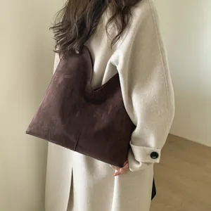 Détail du sac cabas en daim marron foncé avec ouverture en V et finition mate élégante
