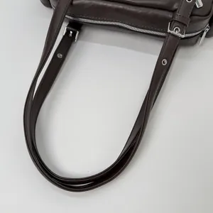 Close-up of adjustable leather straps and silver metal buckle on dark brown shoulder bag