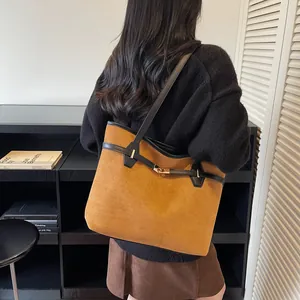 Détail macro du sac cabas en daim marron avec bandoulière noire et fermoir pivotant en métal