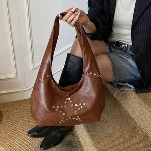 Macro detail of silver star rivets and metallic studs on the brown vintage hobo bag