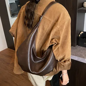 Détail d'un sac demi-lune en cuir marron foncé porté par un mannequin, vue de dos