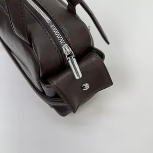 Close-up of vintage brown PU leather shoulder bag featuring silver zipper and rivet details