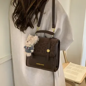 Détail du sac à main en cuir marron avec rabat léopard et pendentif ours mignon