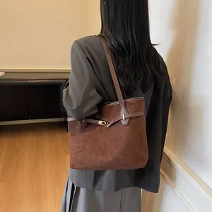 Détail d'un grand cabas en daim marron foncé avec boucle dorée et fine bandoulière