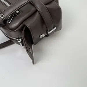Detailed close-up of dark brown leather texture with silver metal zipper and stitching