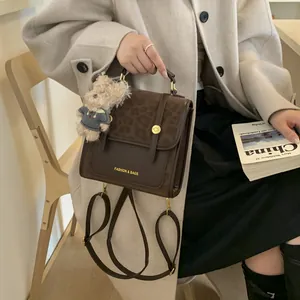 Détail du sac à main en cuir marron avec rabat léopard et breloque ours en peluche mignon