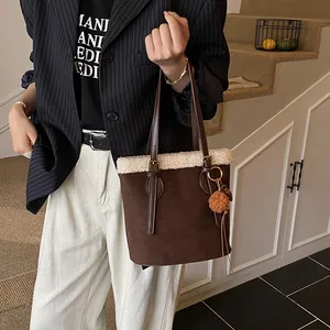 Braune Wildleder-Tasche mit weißem Kunstfellbesatz und Plüsch-Anhänger im Lifestyle-Stil