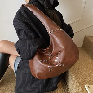Detail view of brown vintage hobo bag with silver metal star rivets on textured leather