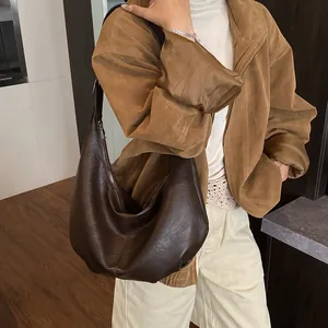 Détail du sac hobo en cuir marron foncé montrant sa grande capacité et son fini brillant