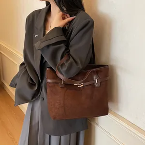 Détail du sac cabas en daim marron foncé avec fermoir rotatif argenté et lanières en cuir