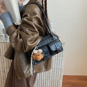Detail of vintage plaid Boston bag with leather accents and a plush poodle charm