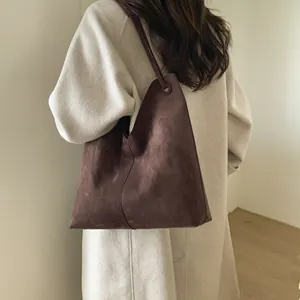 Détail d'un grand sac cabas en daim marron foncé avec texture mate et souple