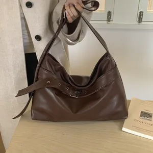 Detailed view of dark brown faux leather tote with decorative silver buckle and soft texture