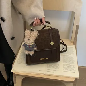 Détail du sac à main marron avec rabat imprimé léopard et breloque ours en peluche