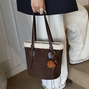Nahaufnahme der braunen Wildleder-Eimertasche mit weißem Teddyfell und Anhängern