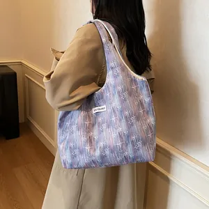 Detail of trendy tote bag with blue abstract print and woven label on beige trench coat