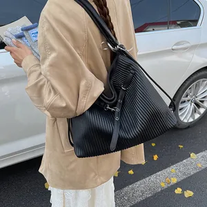 Detail of black pleated hobo bag with adjustable strap shown in street style scene