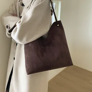 Sac cabas marron foncé en daim avec ouverture en V présenté dans un cadre élégant