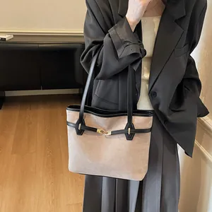 Détail d'un sac cabas vintage en daim beige avec bordure en cuir noir et fermoir doré