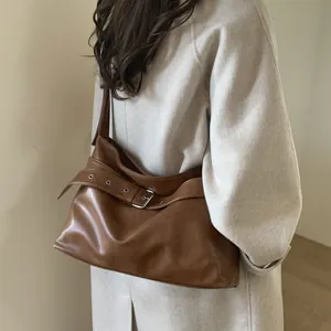 Brown vintage large tote bag detail showing leather strap buckle on model in beige coat