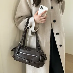 Detail of dark brown faux leather shoulder bag with silver buckles on beige coat