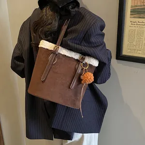 Detail der braunen Wildledertasche mit weißem Kunstpelzbesatz und orangem Plüsch-Anhänger