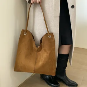 Détail d'un sac cabas en daim marron avec design en V et bandoulière fine élégante