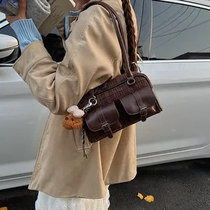 Detail of plaid Boston bag featuring brown leather trim and cute plush bear charm