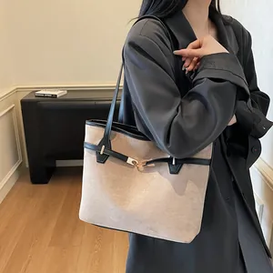 Détail d'un sac cabas en daim beige avec bordures en cuir noir et boucle dorée