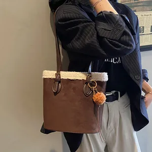 Detailansicht der braunen Wildleder-Beuteltasche mit weißem Plüschrand und Bommel