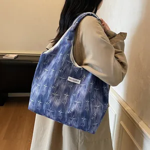 Deep blue tote bag with white star pattern and shoulder strap shown on a model