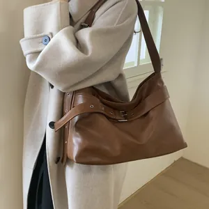 Close-up of caramel brown leather tote bag showing decorative belt and silver buckle