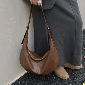 Détail d'un sac hobo marron foncé avec texture en cuir souple et fermeture éclair argentée