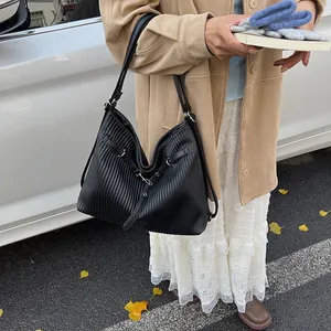 Detail of black pleated tote bag with silver buckle and metallic finish for daily commuting