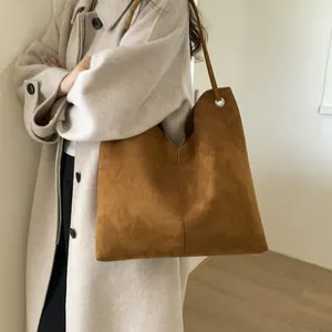 Détail du sac cabas en daim caramel avec fines bandoulières et œillets en métal argenté