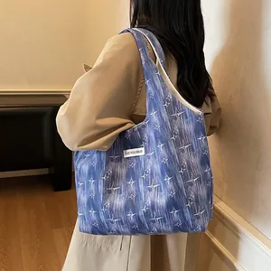 Detail view of the blue tote bag with white star patterns worn over a beige trench coat