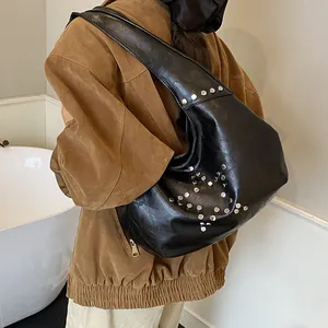 Detailed view of black faux leather hobo bag featuring silver studded star pattern