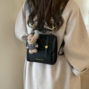 Détail du sac à dos noir avec rabat léopard et breloque en forme d'ours en peluche