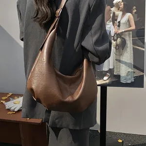 Détails du cuir souple texturé et des coutures sur le sac hobo marron de style rétro