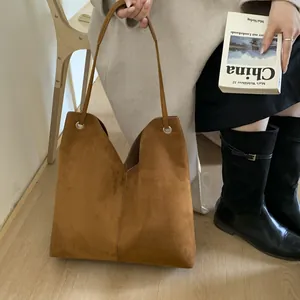 Détail d'un grand sac cabas en daim marron avec ouverture en V et longues poignées